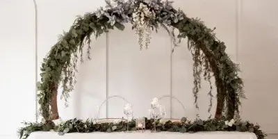 A wedding ceremony setup with a floral arch and a table decorated with candles and greenery.