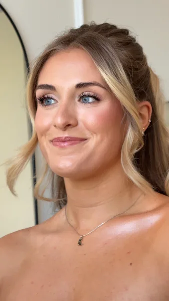 Close-up portrait of a woman with professional bridal makeup and a styled updo.