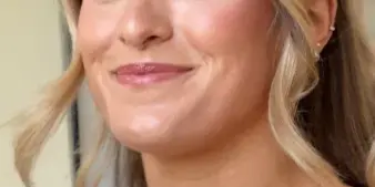 Close-up portrait of a woman with professional bridal makeup and a styled updo.