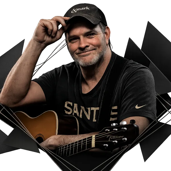 A man with a beard and cap holding an acoustic guitar, representing a live music performer.