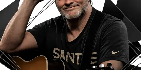 A man with a beard and cap holding an acoustic guitar, representing a live music performer.