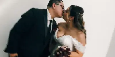 A bride and groom kissing in a white studio setting.