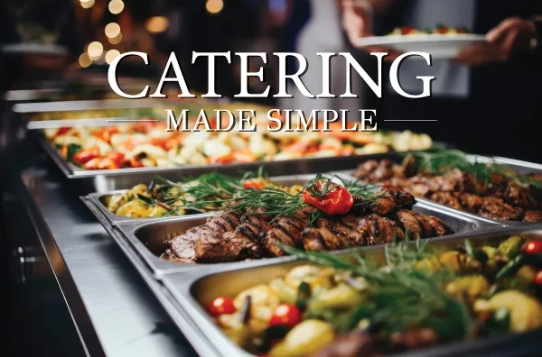 A catering buffet featuring trays of grilled meat, roasted vegetables, and other prepared dishes.