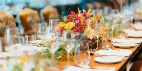 Styled event table with plates, glassware, flatware, and a colorful floral centerpiece