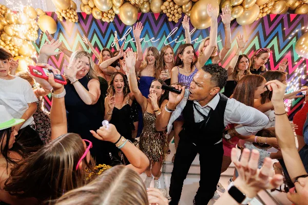 A performer with a microphone interacting with a cheering crowd at a decorated event venue.