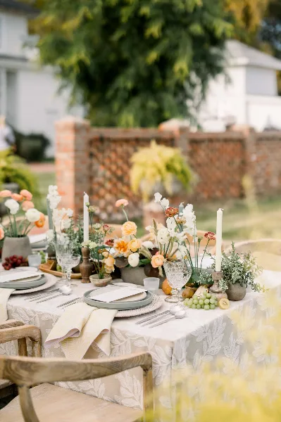 A close-up of an elegantly set wedding table featuring floral centerpieces, tall white candles, and fine dining ware.