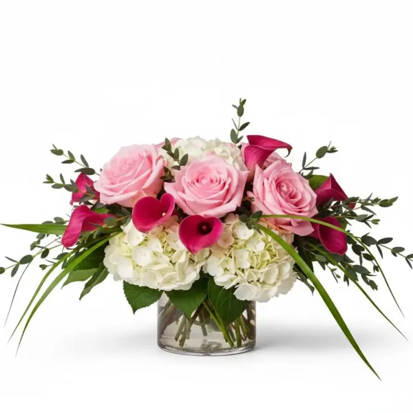 A floral arrangement with pink roses, pink calla lilies, and white hydrangeas in a clear glass vase.