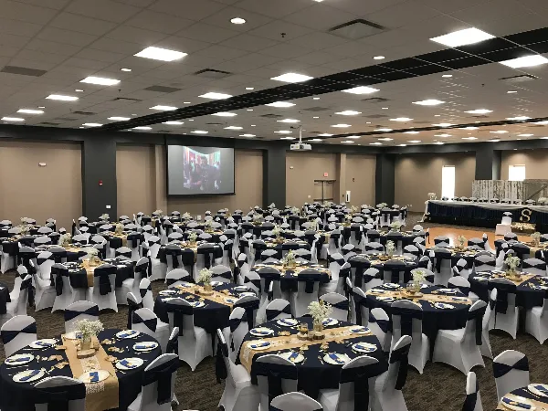 A large banquet hall set up for a wedding reception with round tables, white chair covers, and a head table.