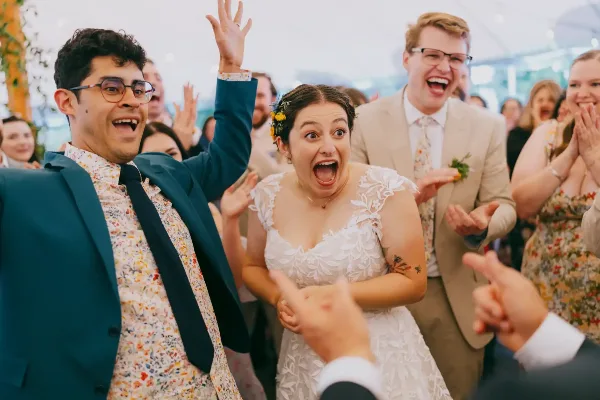 A candid documentary photograph of a bride and groom laughing and celebrating with their wedding guests.
