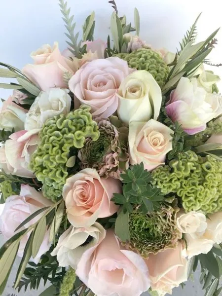 A close-up of a floral arrangement with pink and white roses and greenery