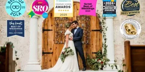 A bride and groom standing in front of a large wooden door with decorative ironwork and stone columns at a wedding venue.