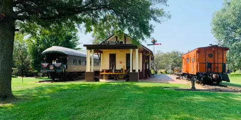 Exterior view of the Panora train depot and historic rail cars at the Guthrie County Historical Village and Museum.