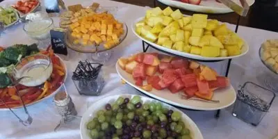 A catering table featuring multiple bowls of fresh fruit including grapes, watermelon, pineapple, and cantaloupe.