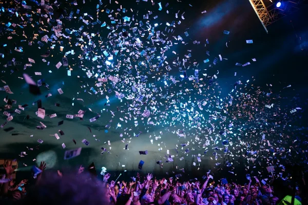 A large crowd of people at an event with confetti falling from the ceiling.