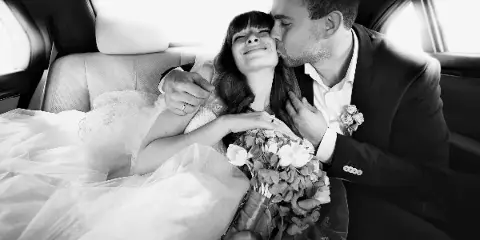 A bride and groom sharing a moment inside a limousine.