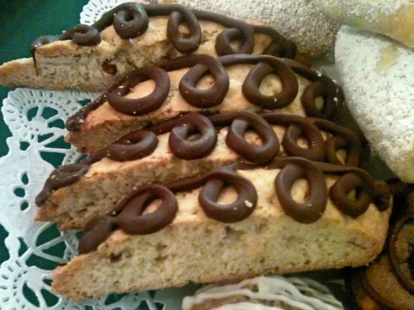 Slices of almond biscotti decorated with chocolate curls on a doily