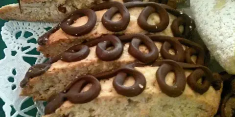 Slices of almond biscotti decorated with chocolate curls on a doily