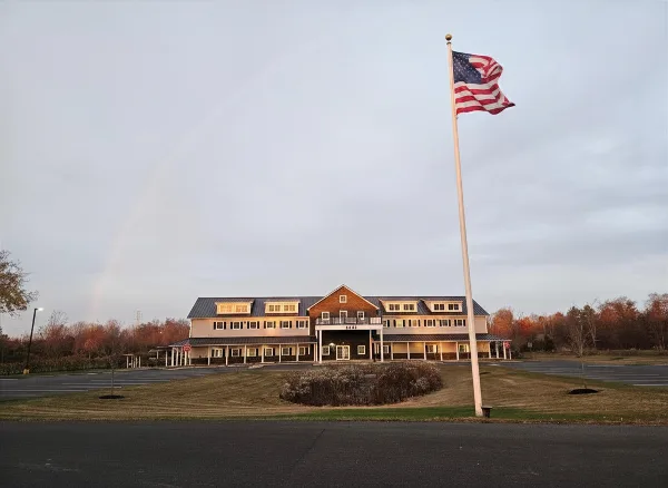 Exterior view of a two-story commercial building with a flagpole and a rainbow in the sky.