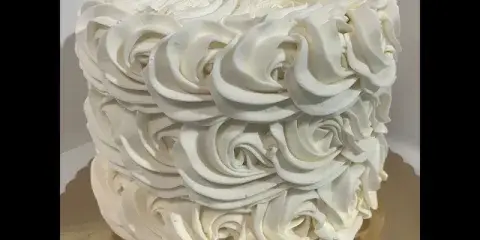 A white wedding cake decorated with piped rosette frosting.