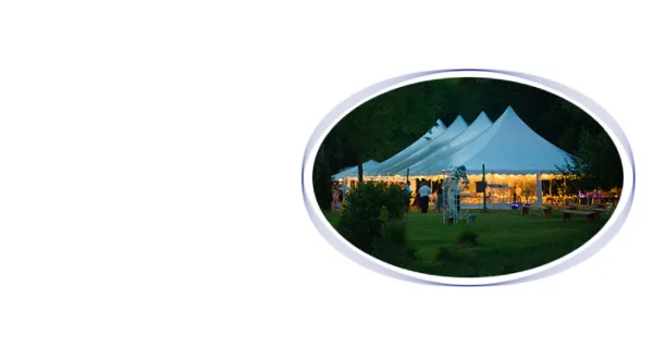 A large white event tent set up on a grassy lawn at dusk.