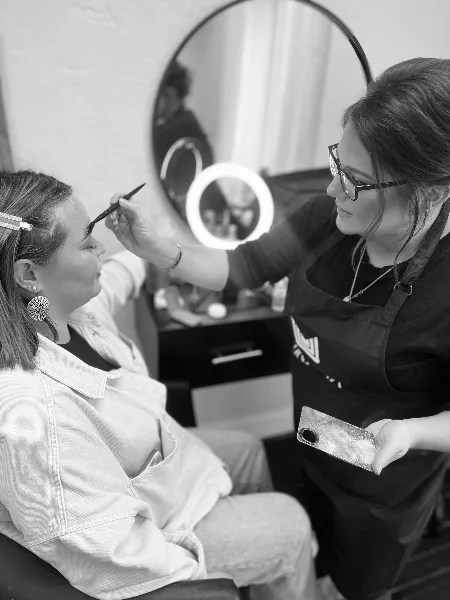 A makeup artist applying makeup to a client's face in a salon setting.