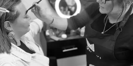 A makeup artist applying makeup to a client's face in a salon setting.