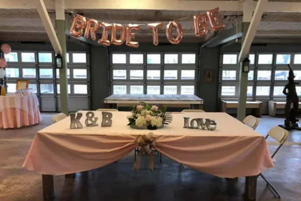 Interior of a wedding venue with a table decorated with 'Bride to Be' balloons and 'K&B Love' signs.
