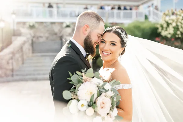 A professional wedding photograph of a bride and groom sharing an intimate moment outdoors.