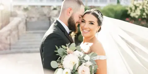 A professional wedding photograph of a bride and groom sharing an intimate moment outdoors.