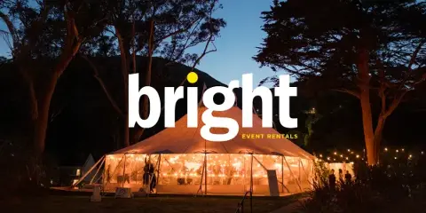 An illuminated white event tent set up outdoors at dusk with the Bright Event Rentals logo overlaid.