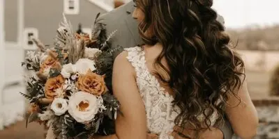 Bride with wavy braided wedding hair holding a bouquet of earth-toned flowers