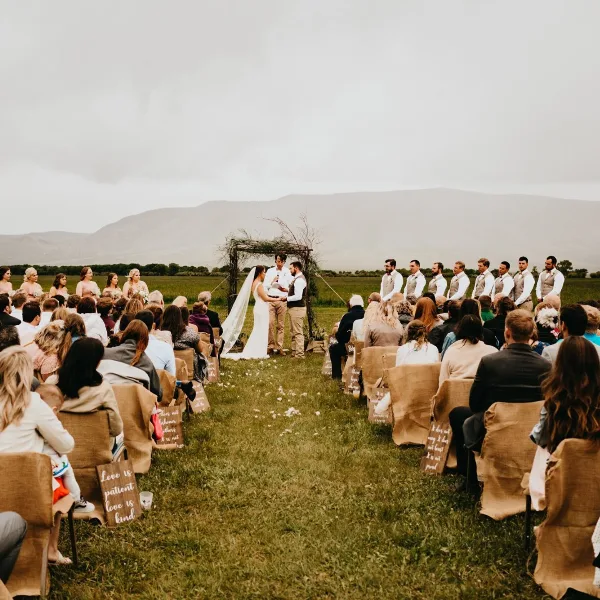 Outdoor wedding ceremony at a rustic venue with a wooden arch and mountain views
