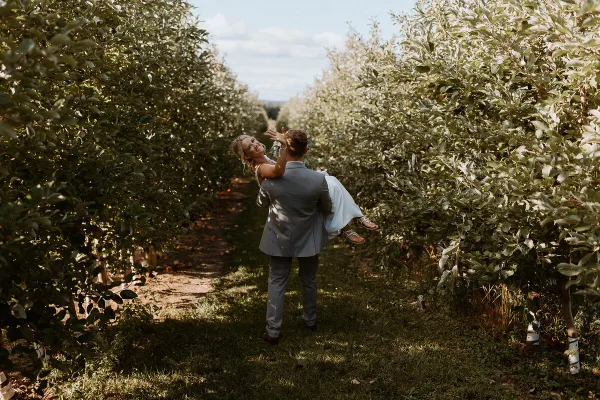 A bride and groom dancing in the aisle of an apple orchard.
