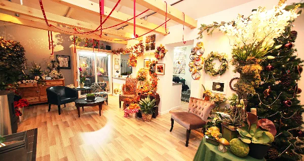 Interior view of a floral boutique featuring various flower arrangements, wreaths, and a decorated Christmas tree.
