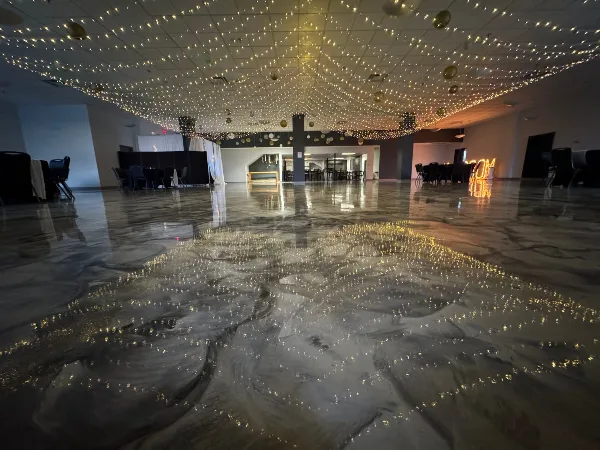 Interior view of a large event hall with polished marbled floors and a ceiling covered in string lights.