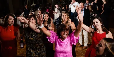 Wedding guests dancing together on a packed reception dance floor.
