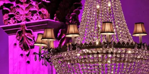Interior view of a wedding venue featuring a large crystal chandelier and ornate architectural details illuminated by purple lighting.