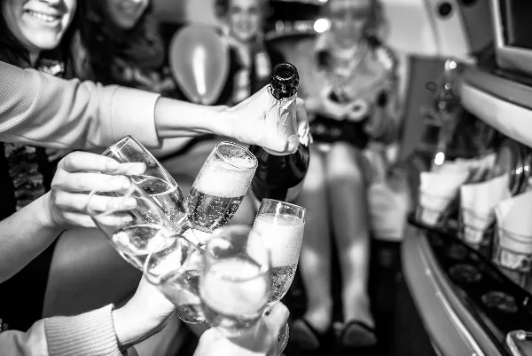 People toasting with champagne flutes inside a party bus or limousine.