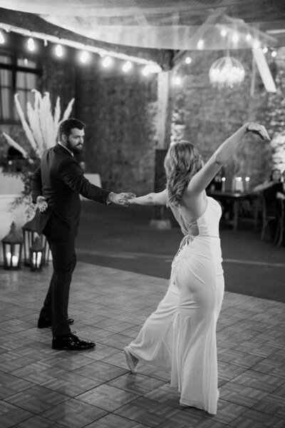 A black and white photograph of a bride and groom dancing at a wedding reception.