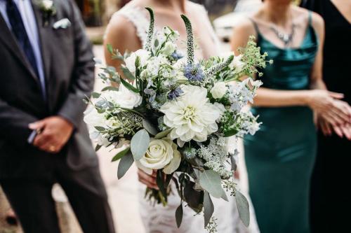 A bride holding a white and green floral bouquet during a wedding ceremony.