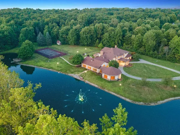 Aerial view of the Medina Mansion venue showing the large house, private pond, tennis court, and surrounding wooded property.