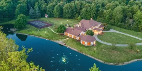 Aerial view of the Medina Mansion venue showing the large house, private pond, tennis court, and surrounding wooded property.