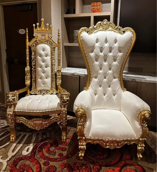 Two ornate gold and white throne chairs with tufted upholstery and decorative gold frames.