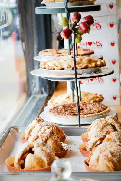A tiered display stand holding various baked goods including pies and pastries in a bakery setting.