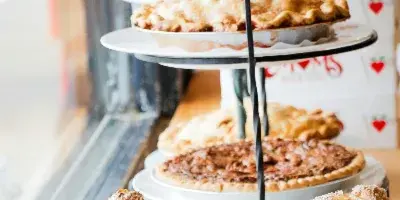 A tiered display stand holding various baked goods including pies and pastries in a bakery setting.