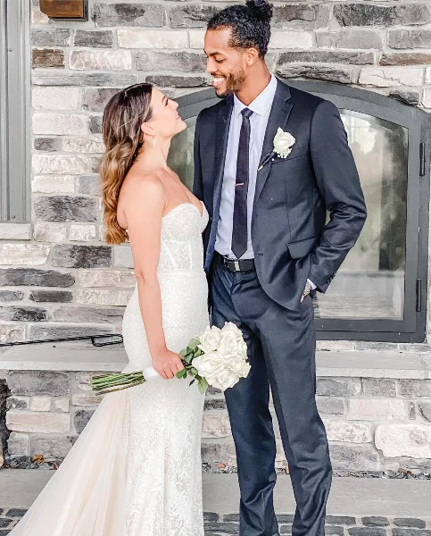 A bride and groom standing together in front of a stone fireplace at a wedding venue.