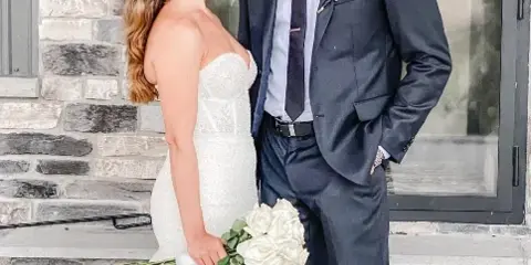 A bride and groom standing together in front of a stone fireplace at a wedding venue.