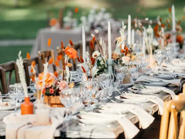 A close-up view of a long event table set with white linens, glassware, and floral centerpieces.