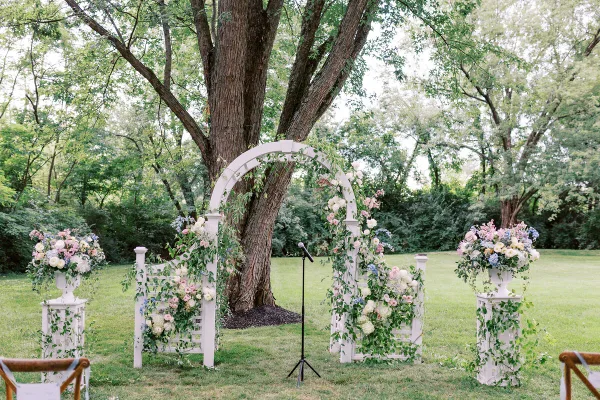 Outdoor wedding ceremony arch decorated with flowers and greenery in a wooded venue setting