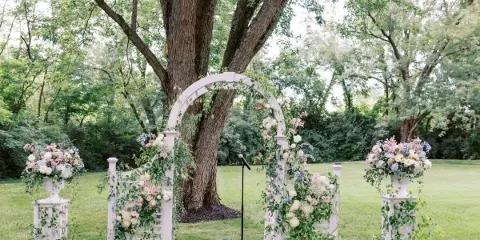 Outdoor wedding ceremony arch decorated with flowers and greenery in a wooded venue setting